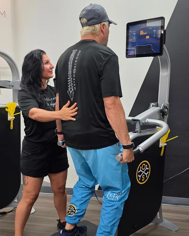 A coach places a hand on a member's back as he lifts upward at the postural station